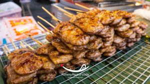 Moo Ping (grilled pork Street Food in Thailand) Smoky skewers on a wooden stick